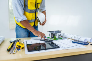 A person using a calculator on a desk with construction documents in Meridian.