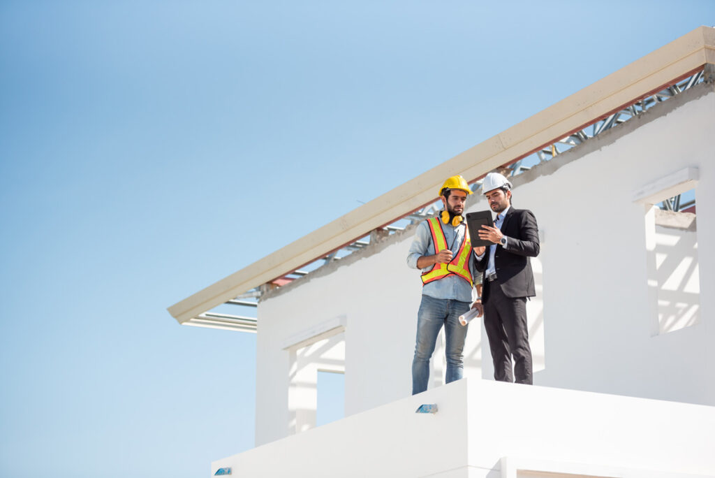 Two professionals standing on a white building going over commercial construction project plans in Treasure Valley.