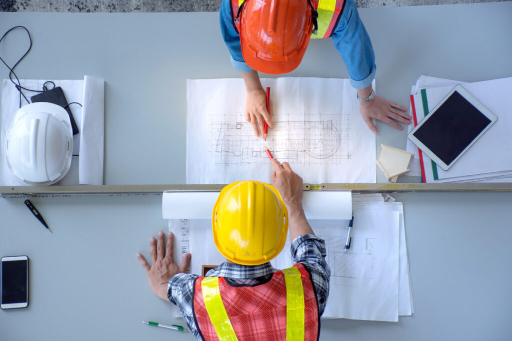 An above view of two construction personnel reviewing blueprints for a construction site in Meridian.