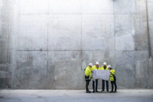 Four members of a Meridian design build construction team reviewing blueprints.