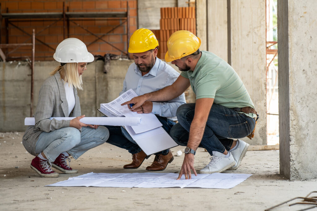 The professionals in hard hats reviewing blueprints at a Meridian construction site.